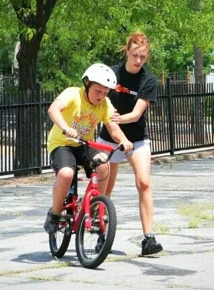child on bike while adult steadies the bike